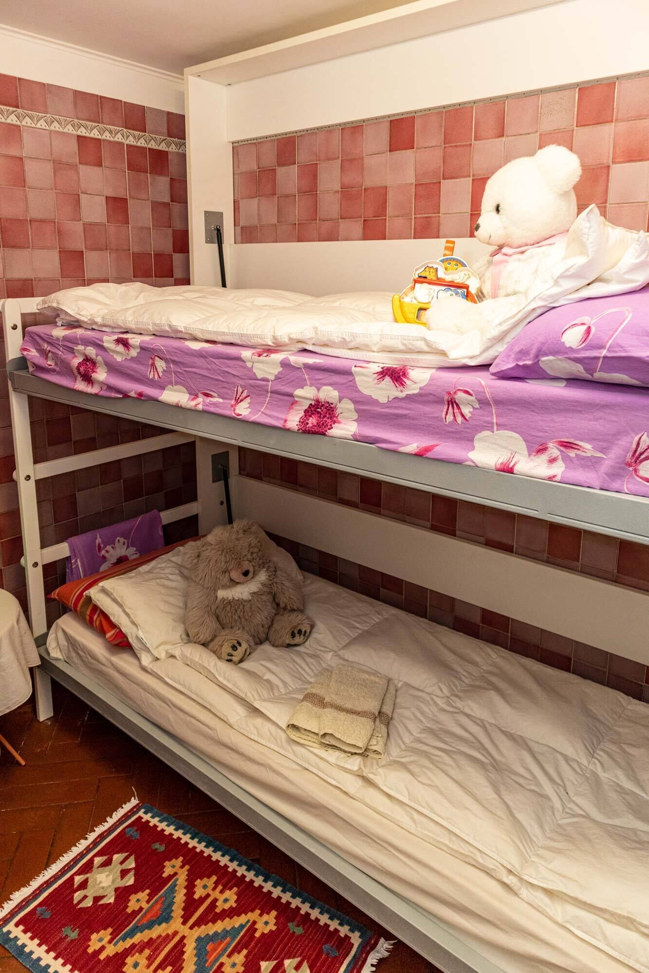 Habitación con literas, un oso de peluche en la cama inferior y un oso de peluche blanco en la superior.