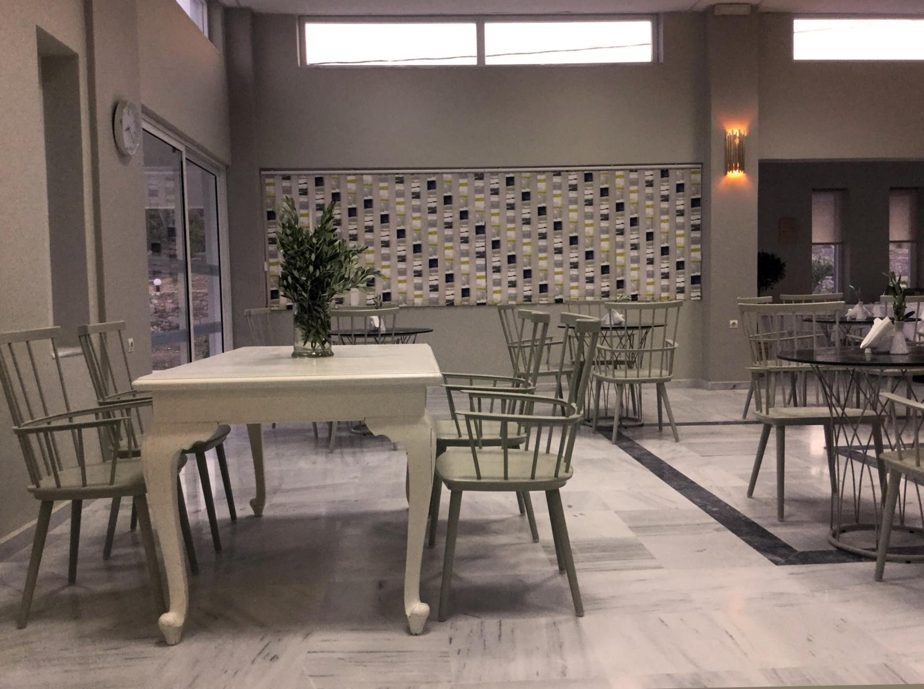 A dining area with a white table and chairs, a decorative plant, and a patterned wall in the background.