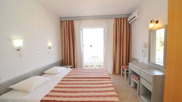A hotel room with a bed, a desk, a chair, a mirror, and a window with curtains.