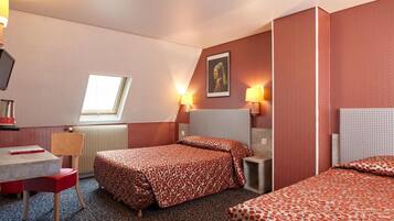 Habitación de hotel con dos camas, un escritorio, una silla, un radiador y una ventana.