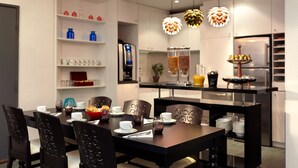 A modern dining area with a dark wooden table, black chairs, and a white shelf with various items. - Hôtel Miramar (Paris)