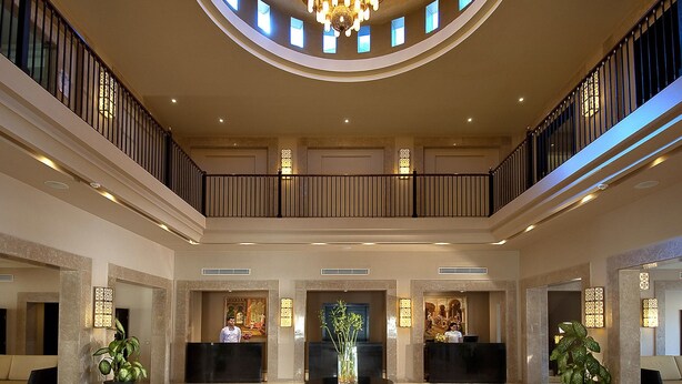 A spacious lobby with a central reception desk, two receptionists, a chandelier, and a circular floor design. - SENTIDO Reef Oasis Aqua Park Resort - All inclusive (Sharm El Sheikh)
