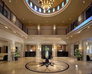 A spacious lobby with a central reception desk, two receptionists, a chandelier, and a circular floor design. - SENTIDO Reef Oasis Aqua Park Resort - All inclusive (Sharm El Sheikh)