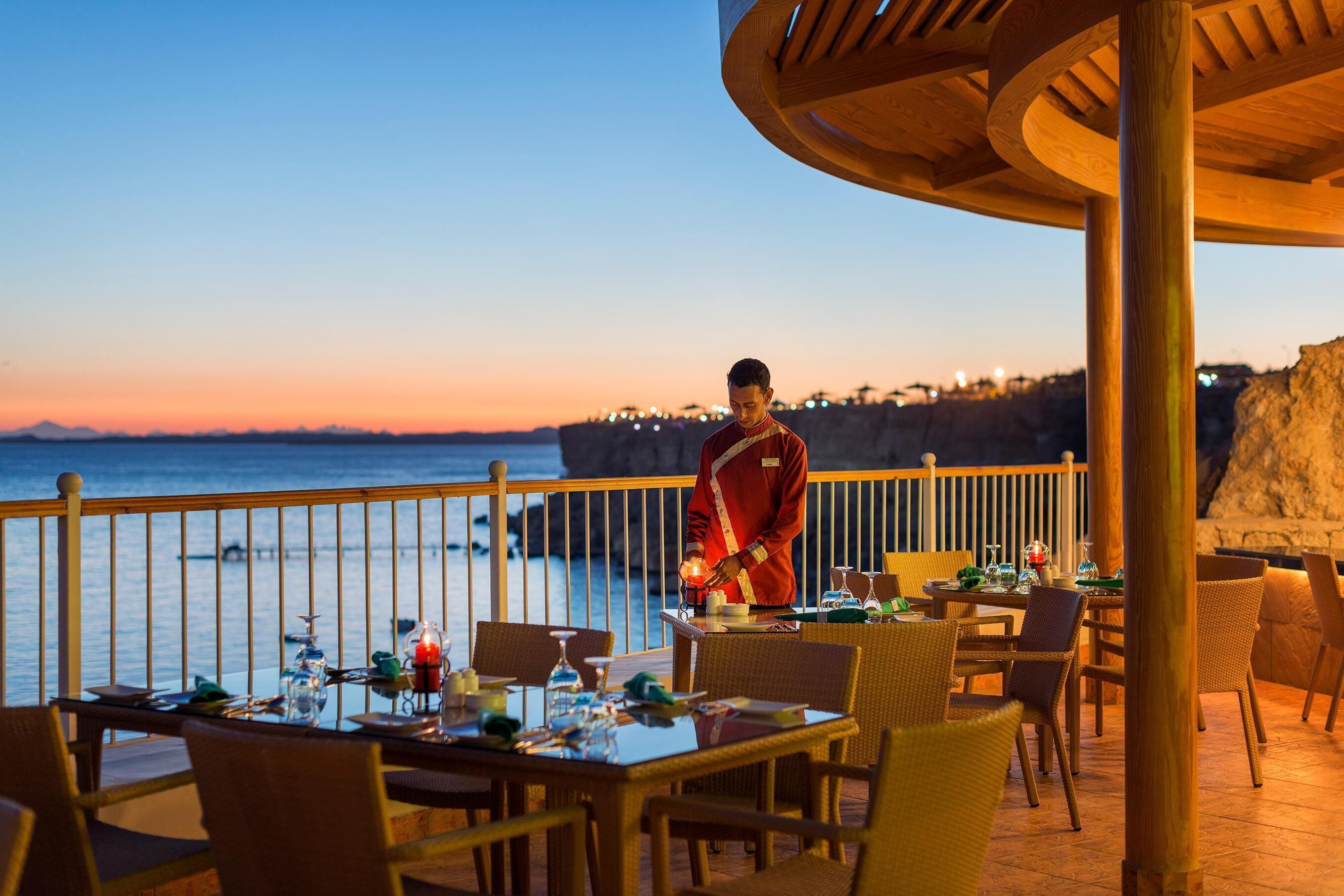 Comedor con mesas dispuestas para una comida, con vistas a la costa.