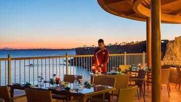 Comedor con mesas dispuestas para una comida, con vistas a la costa.
