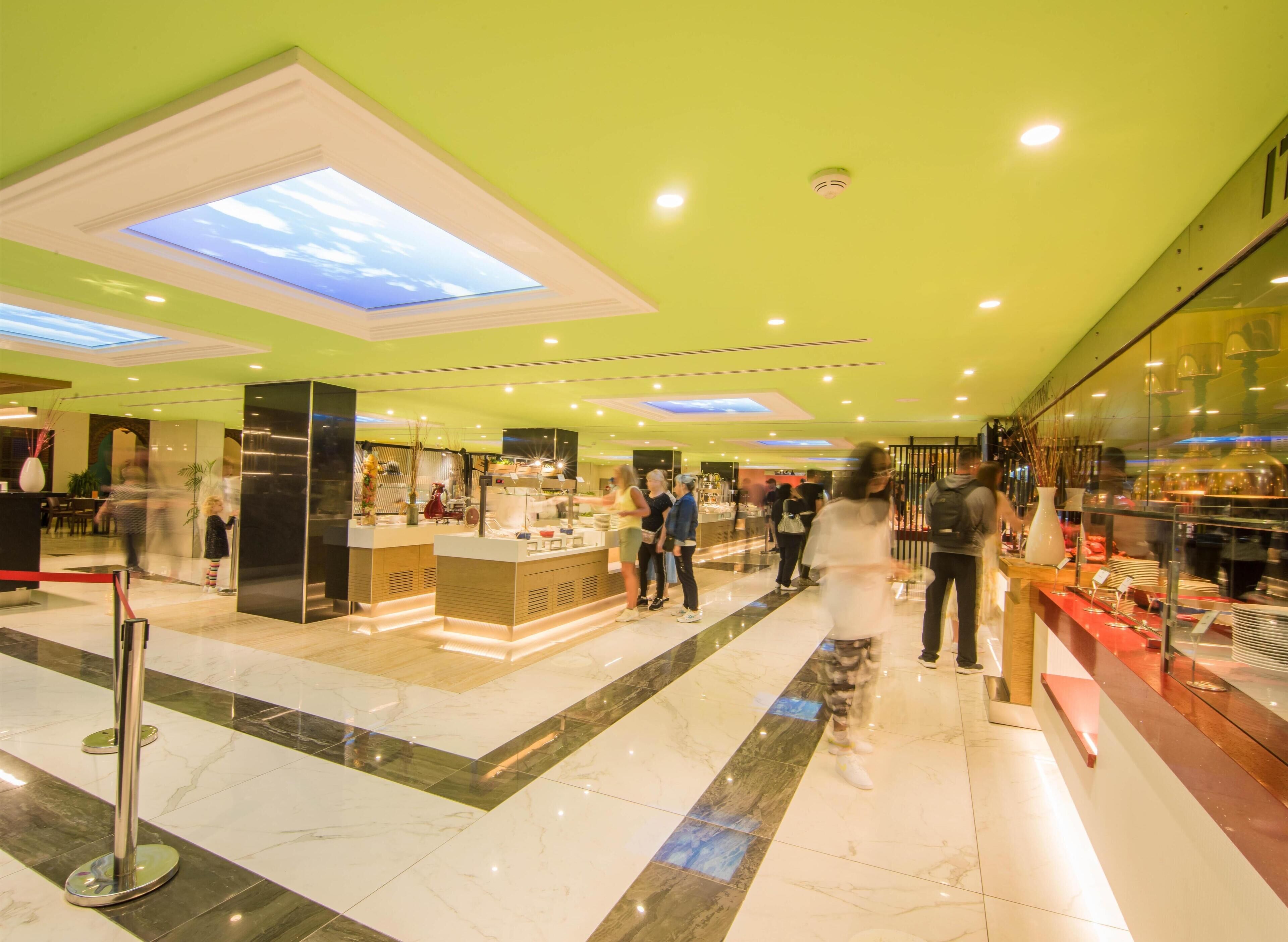 A modern interior with a central counter, glass display cases, and a green ceiling.