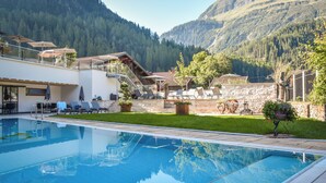 A pool area with lounge chairs, a staircase, and a view of mountains.