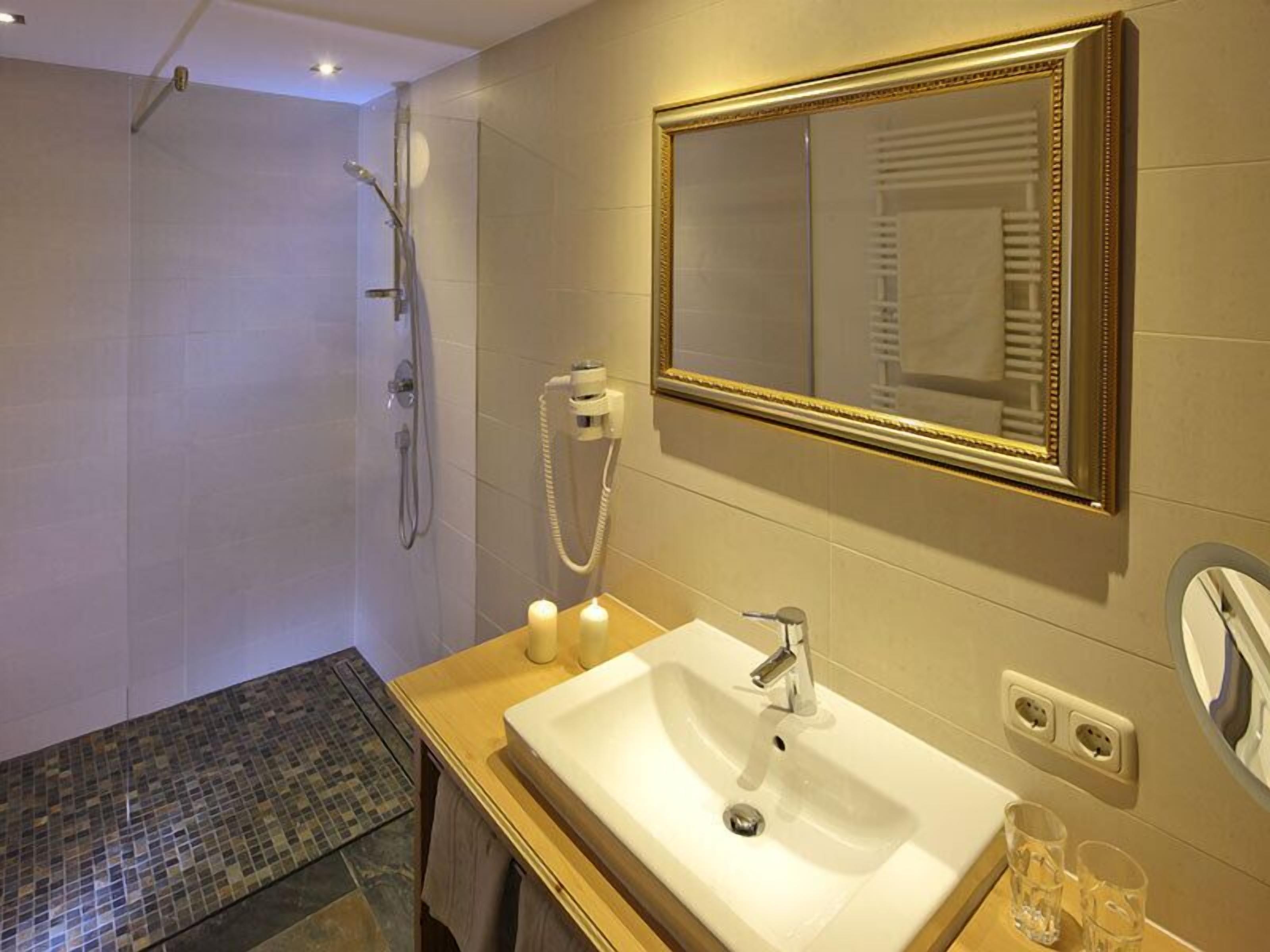 Une salle de bain moderne avec un grand miroir, un lavabo et une douche.