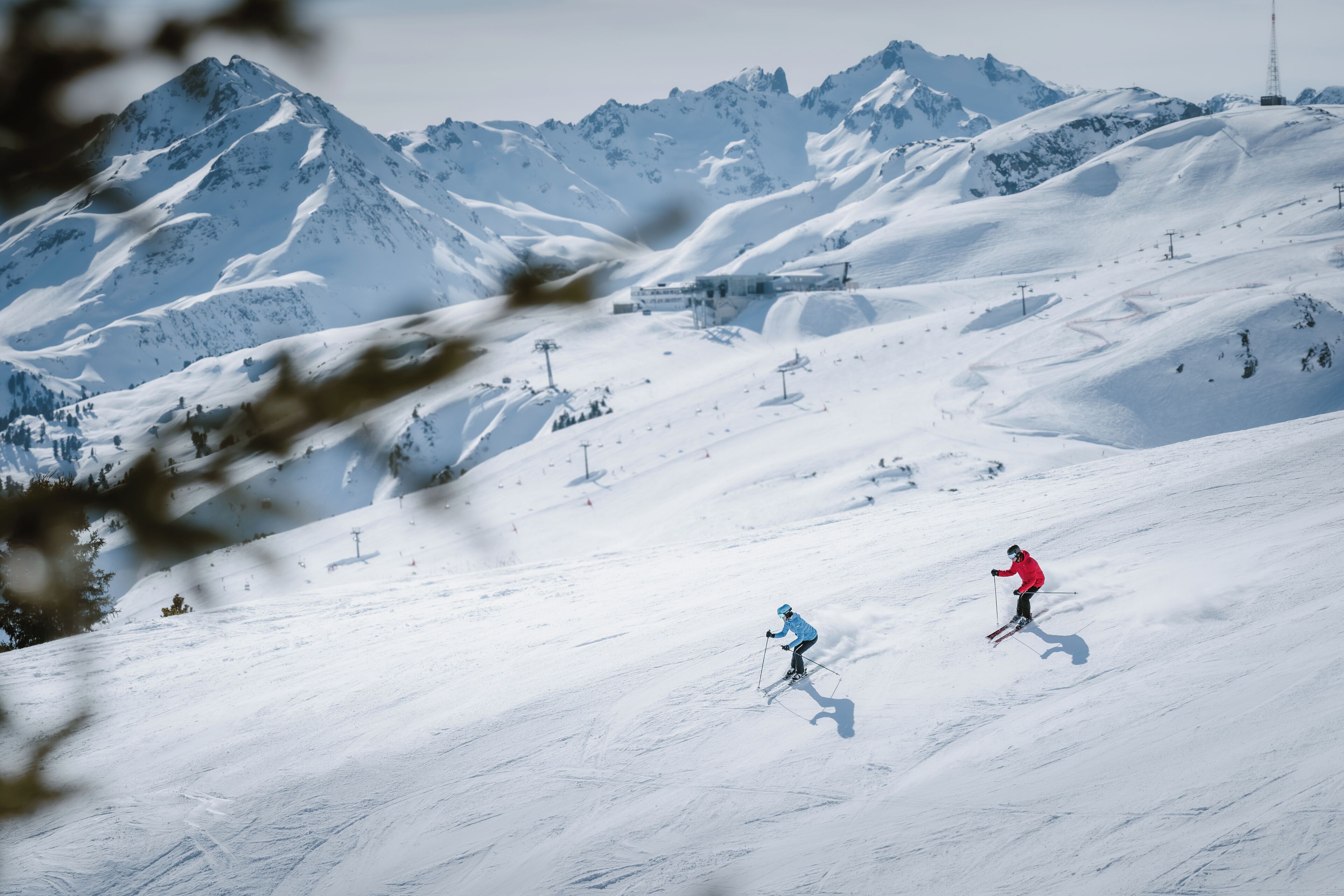 Una pista de esquí nevada con esquiadores, un telesilla y una montaña al fondo.