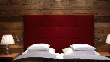 A bed with a red upholstered headboard, white pillows, and a dark fur throw.