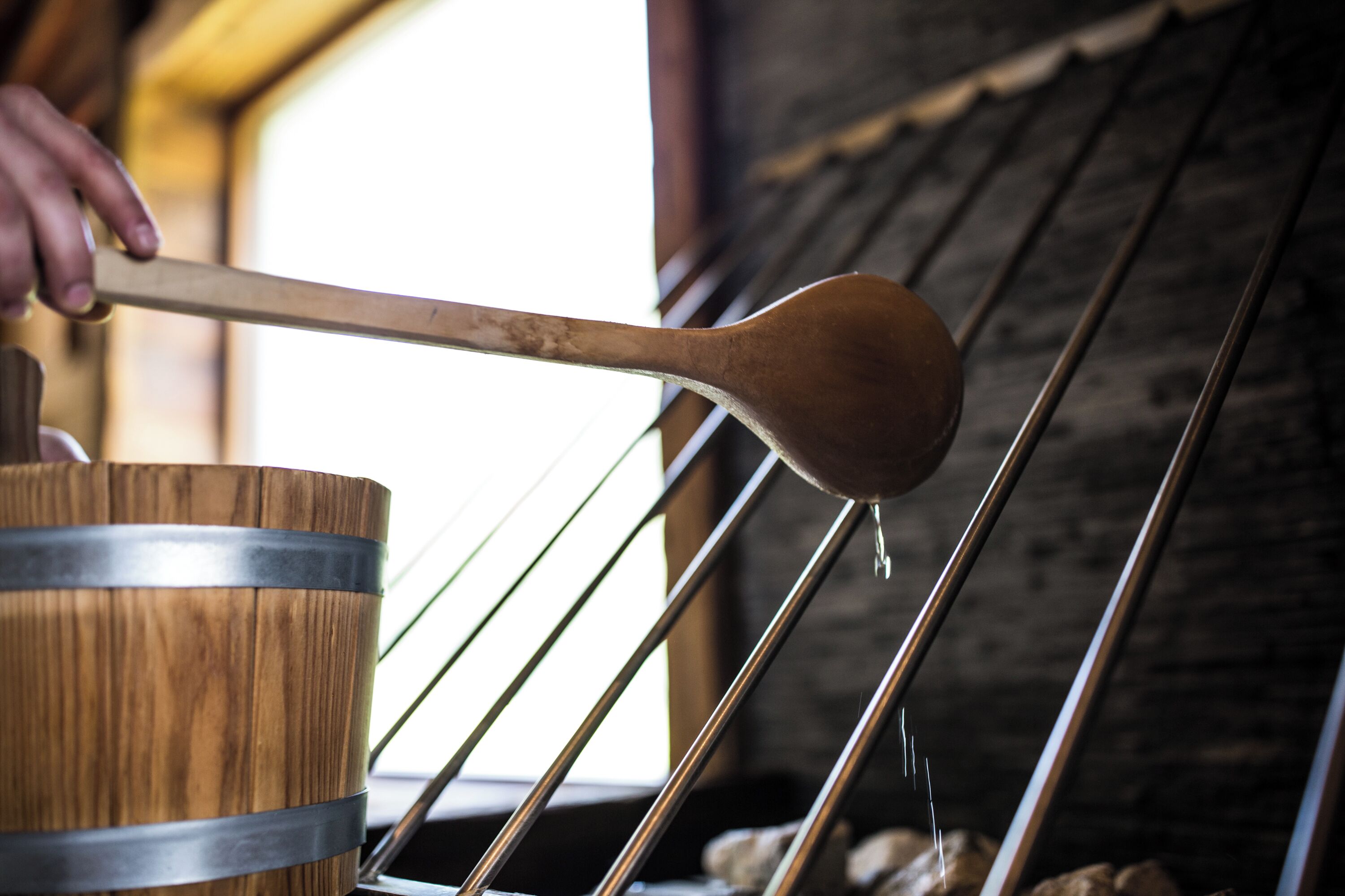 A wooden barrel with metal bands, a wooden ladle, and metal rods in a rustic setting.