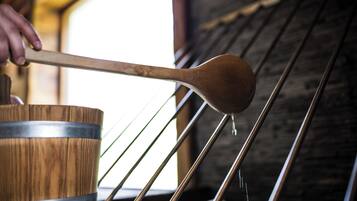 A wooden barrel with metal bands, a wooden ladle, and metal rods in a rustic setting.