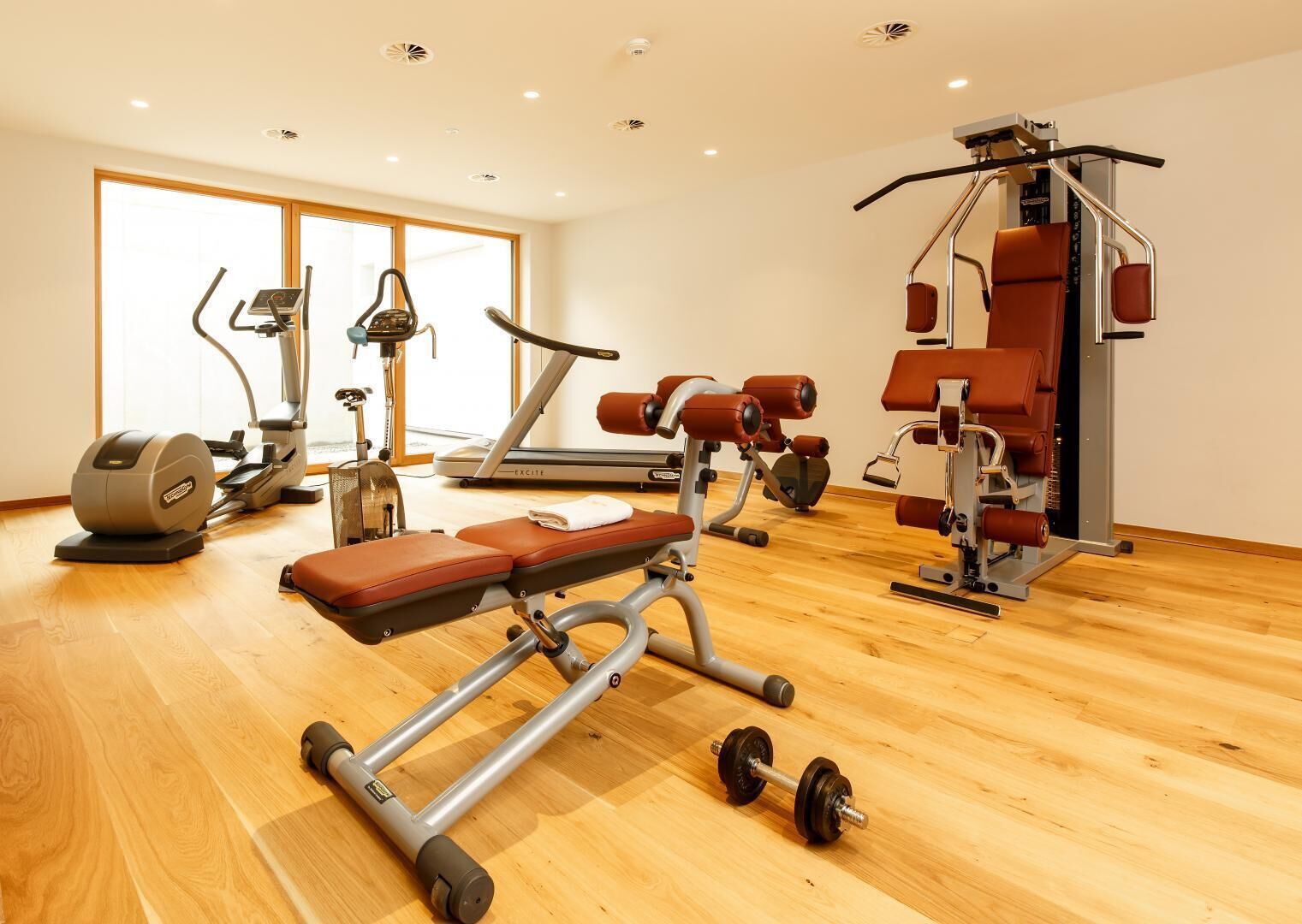 Una sala de gimnàstica amb màquines cardiovasculars, equip d'aixecament de peses i una banca.