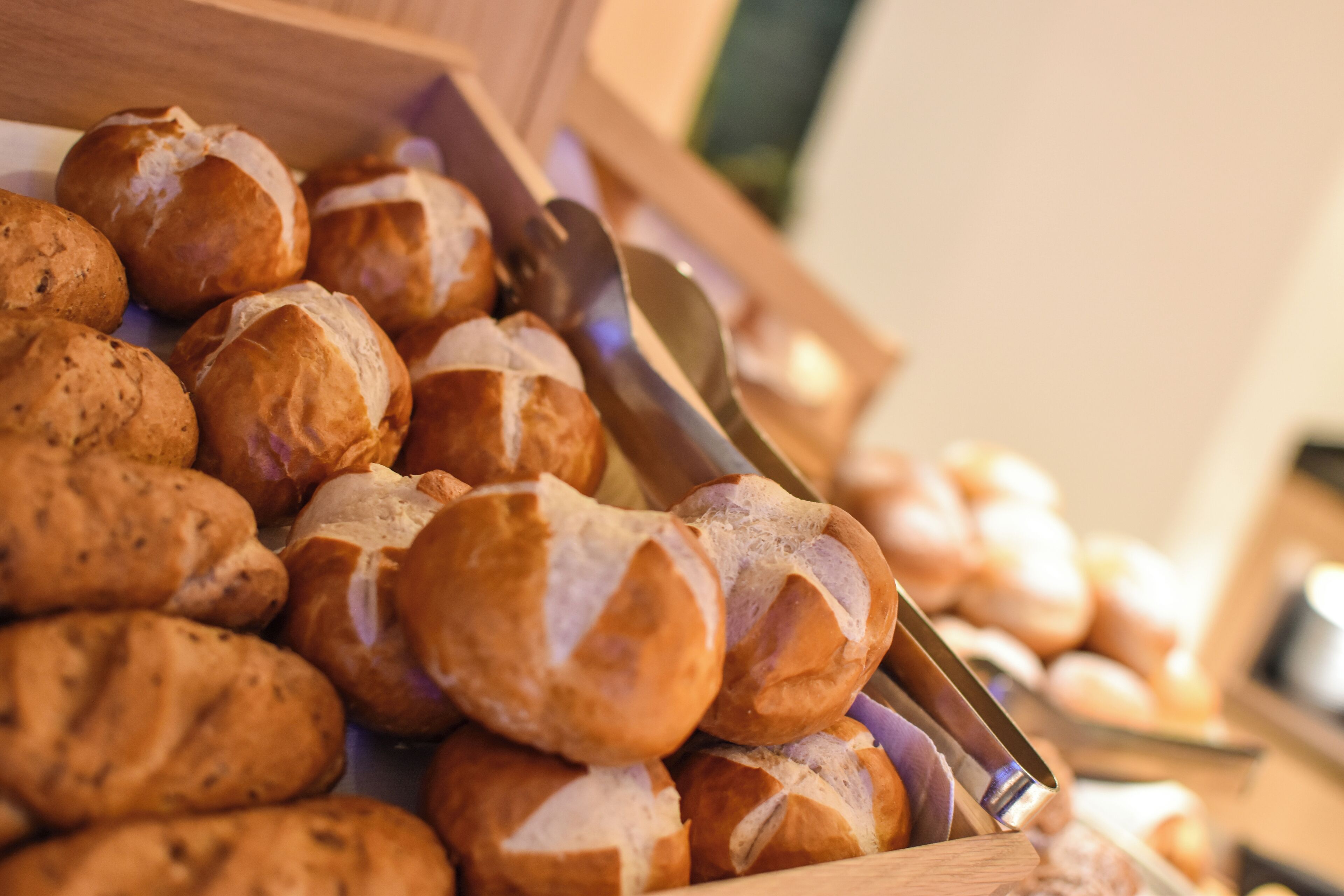 A wooden box filled with various types of bread rolls.