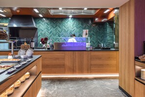 A modern kitchen with wooden cabinets, a herringbone tile backsplash, and a central island with a blue-lit screen.