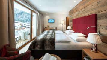 A modern hotel room with a large bed, a wooden headboard, a view of a snowy mountain, and a wooden wall.