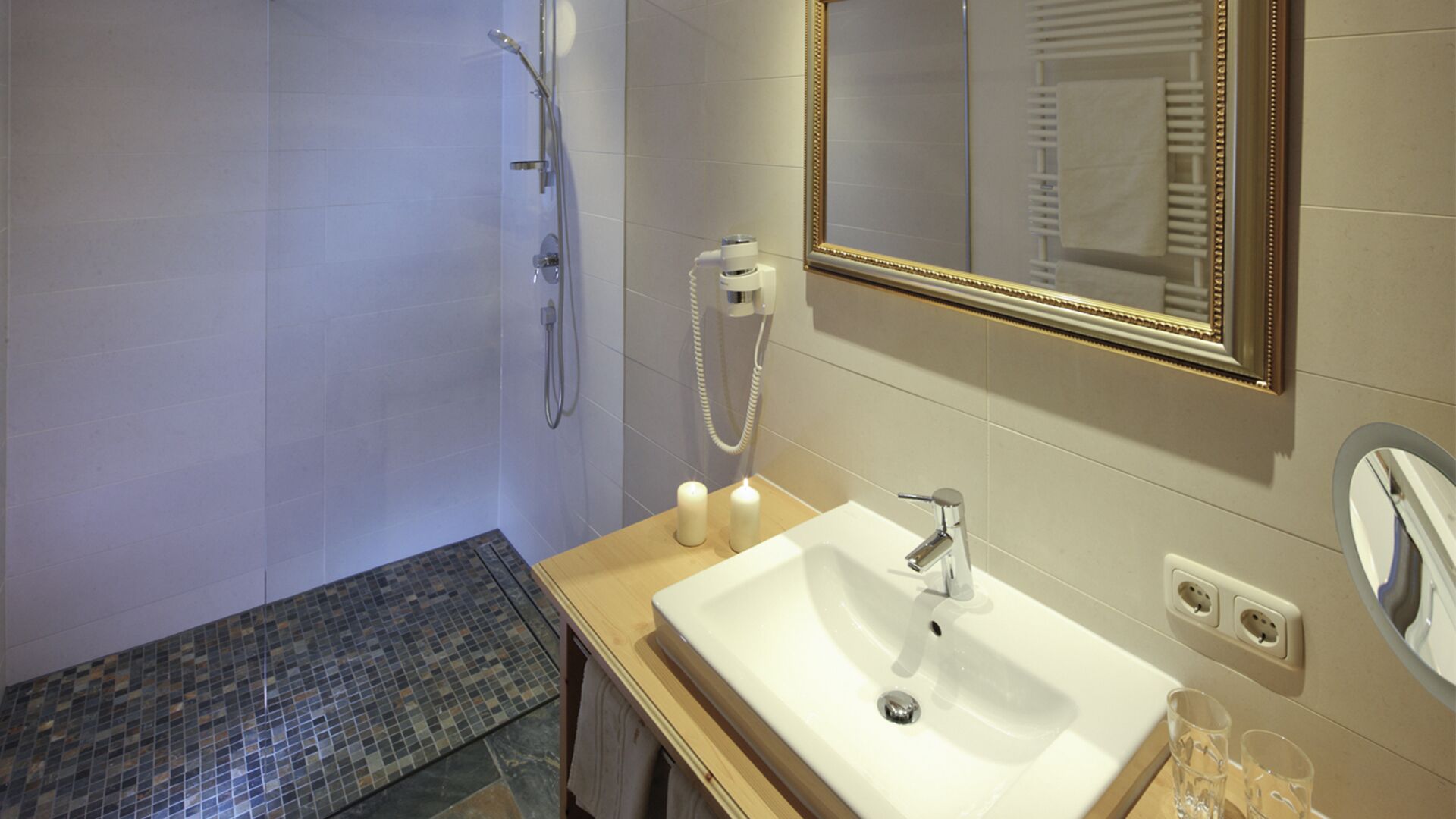 Ein Badezimmer mit Dusche, Waschbecken, Spiegel und Handtuchhalter.