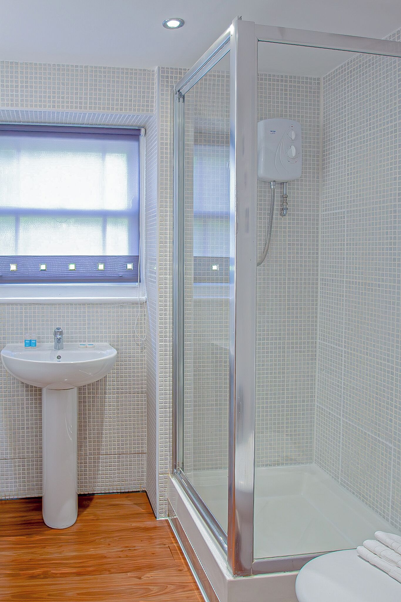 A bathroom with a shower, a sink, and a window.