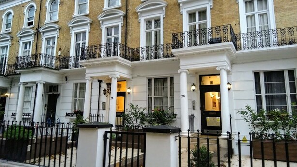 A row of traditional terraced houses with white facades and black iron balconies. - Imperial Court Studios (London)