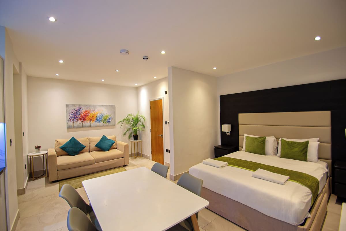 Een hotelkamer met een bed, een slaapbank, een eettafel en een schilderij aan de muur.
