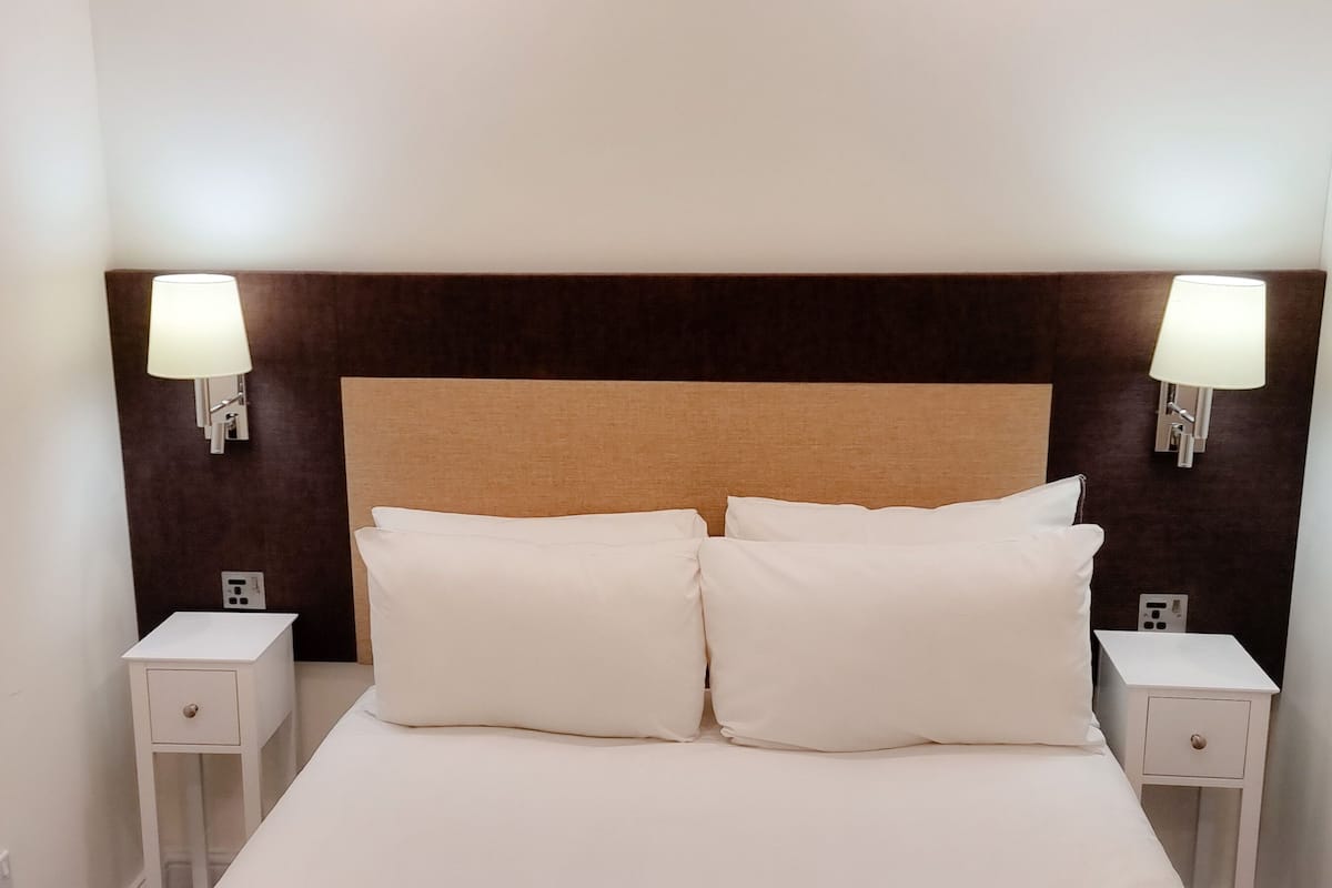 Een hotelkamer met een groot bed, twee nachtkastjes en wandlampen.