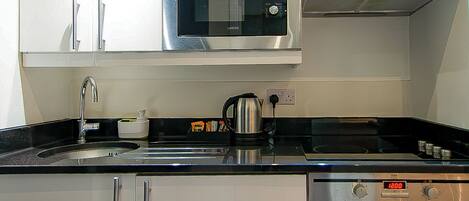 Una cocina moderna con electrodomésticos de acero inoxidable, armarios blancos y piso de madera.