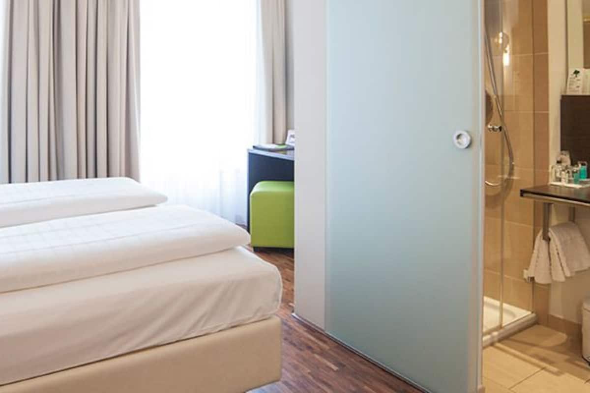 Quarto de hotel com cama, banheiro e vista para o exterior.