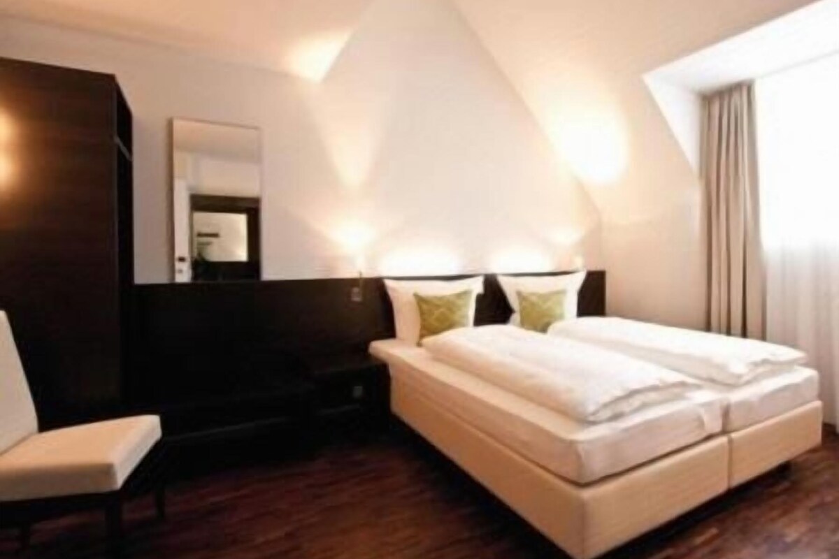 Ein Schlafzimmer mit einem großen Bett, einem Sessel und einem dunklen Wandschrank.
