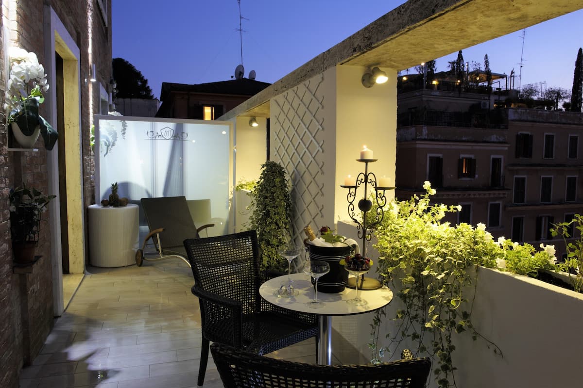 A balcony with a table, chairs, and potted plants.