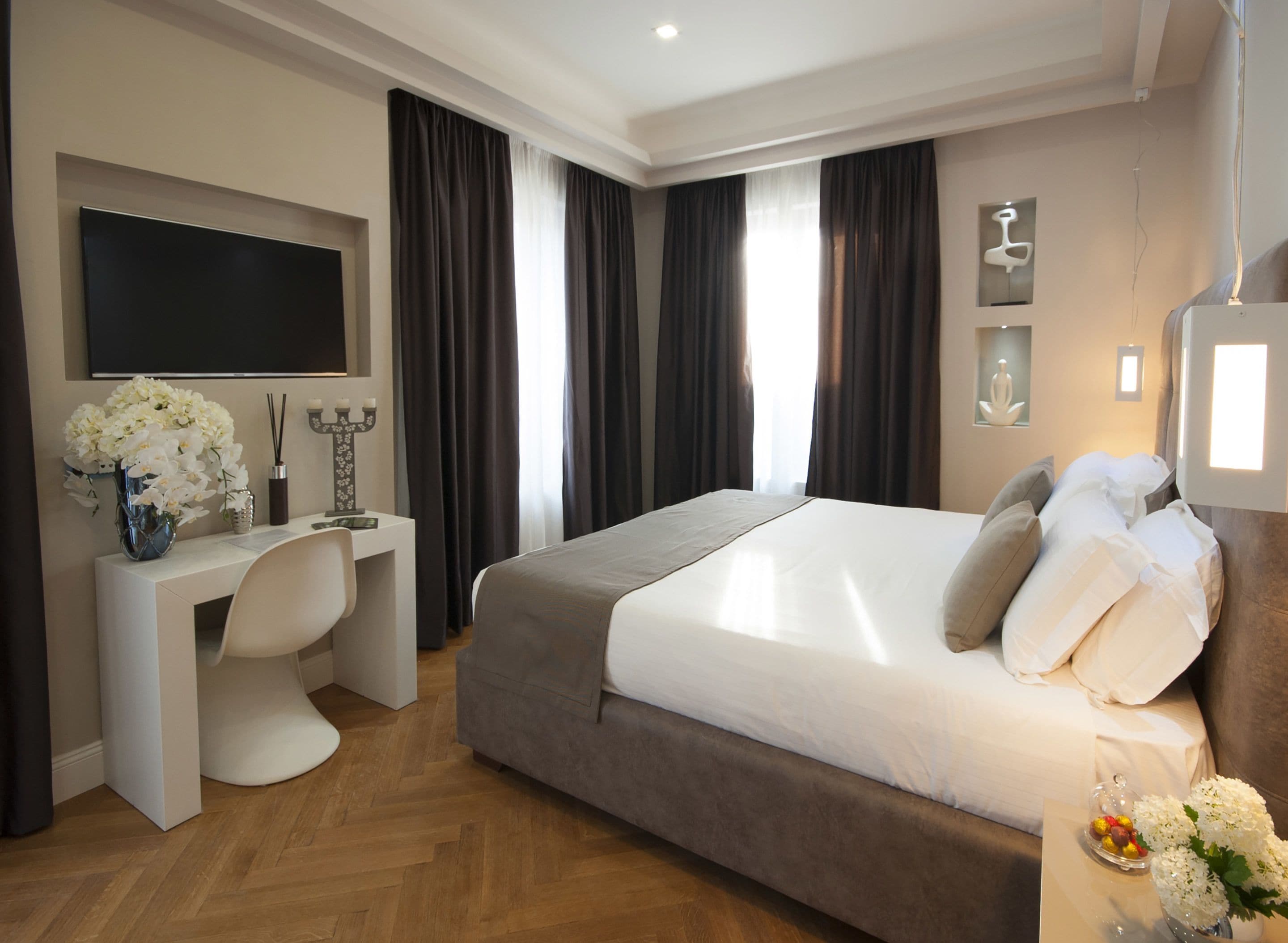 Ein modernes Hotelzimmer mit einem großen Bett, einem Schreibtisch und einem Fernseher.