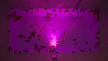 Una stanza con una fontana illuminata di viola e petali di rosa sparsi sul pavimento.