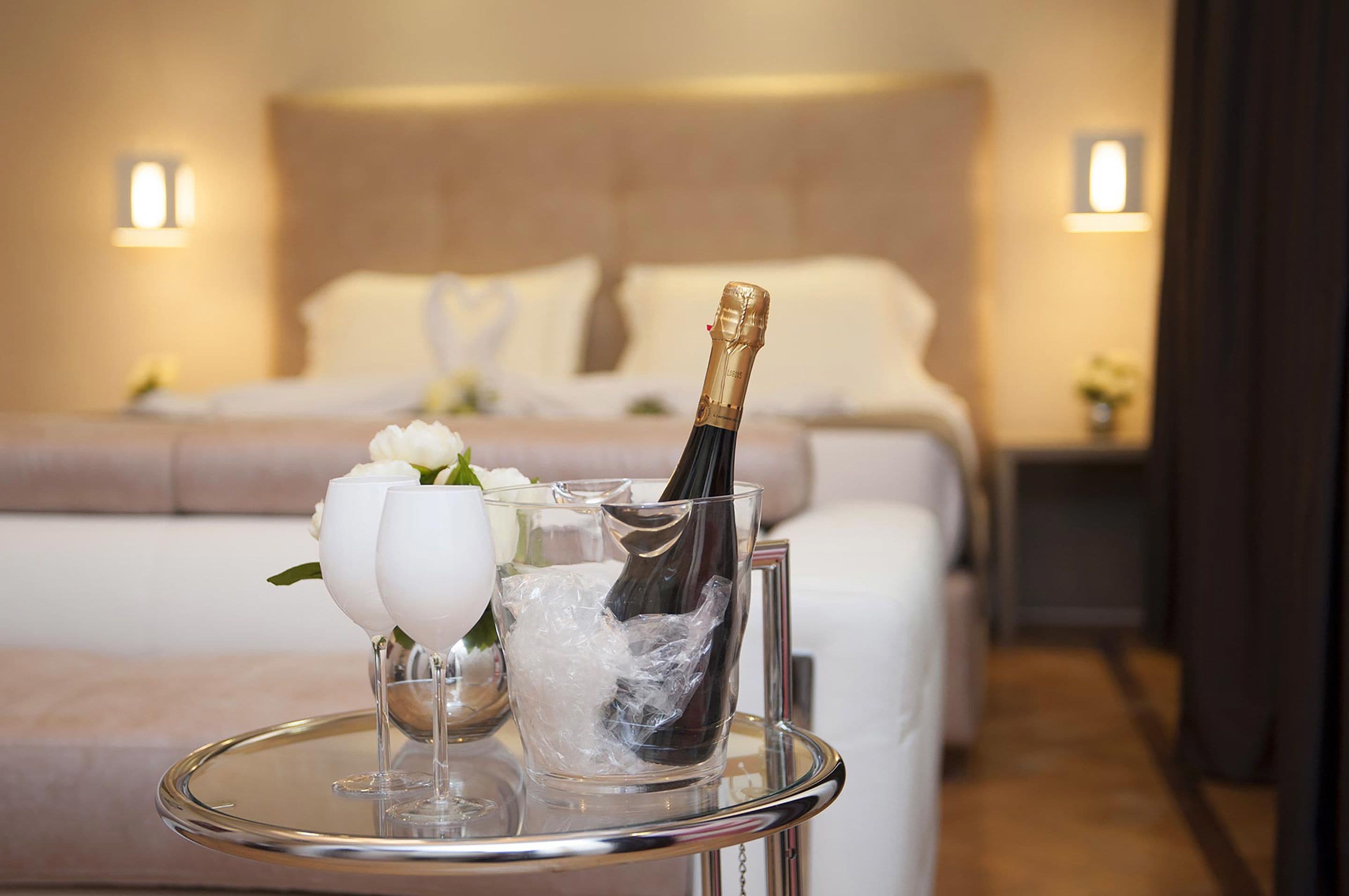 Ein Zimmer mit einem Bett, einem Nachttisch und einer Champagnerflasche auf dem Tisch.