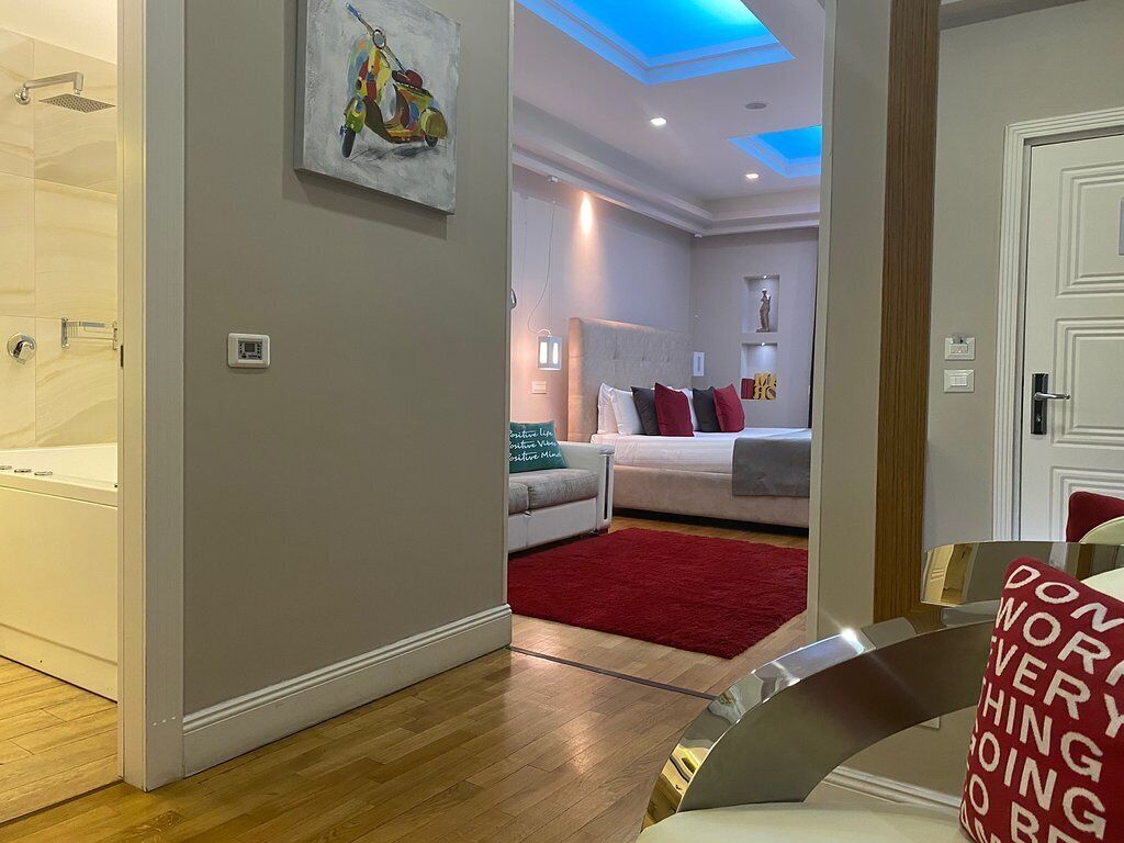 A modern bedroom with a large bed, a red rug, and a ceiling with blue lighting.