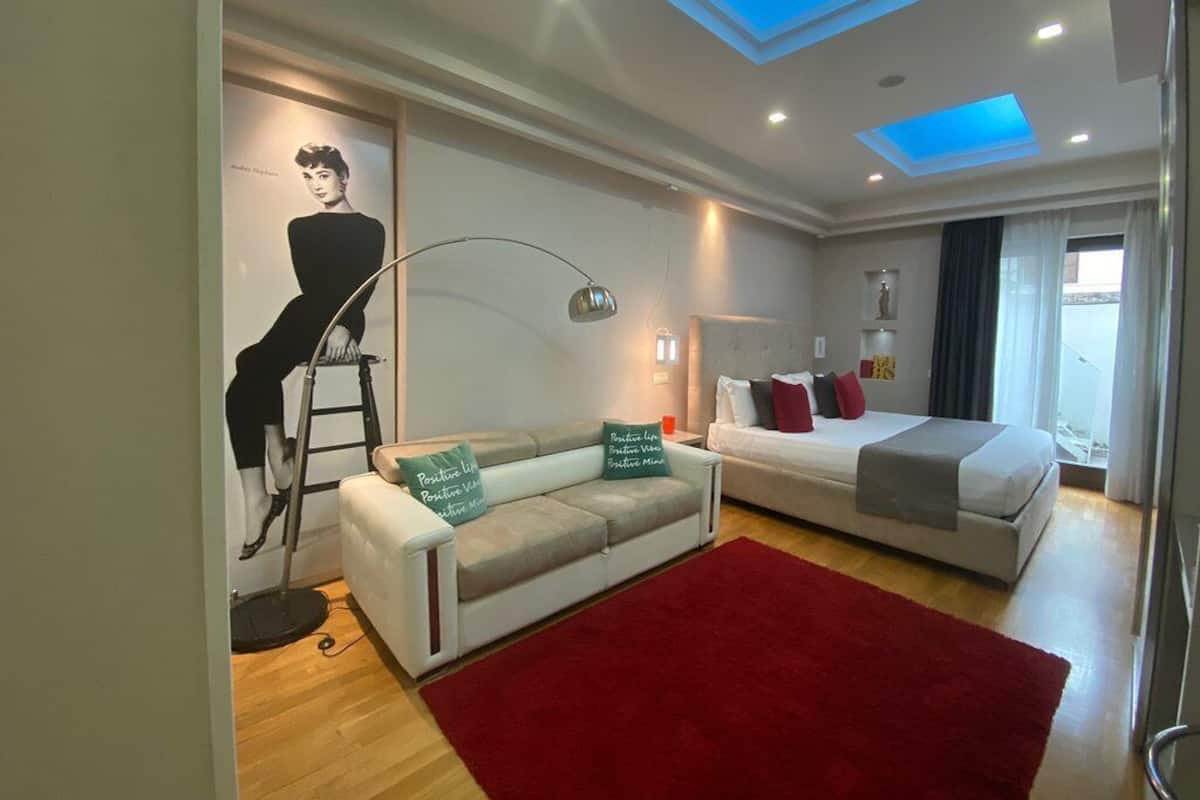 A modern hotel room with a skylight, a sofa, a bed, and a mannequin.