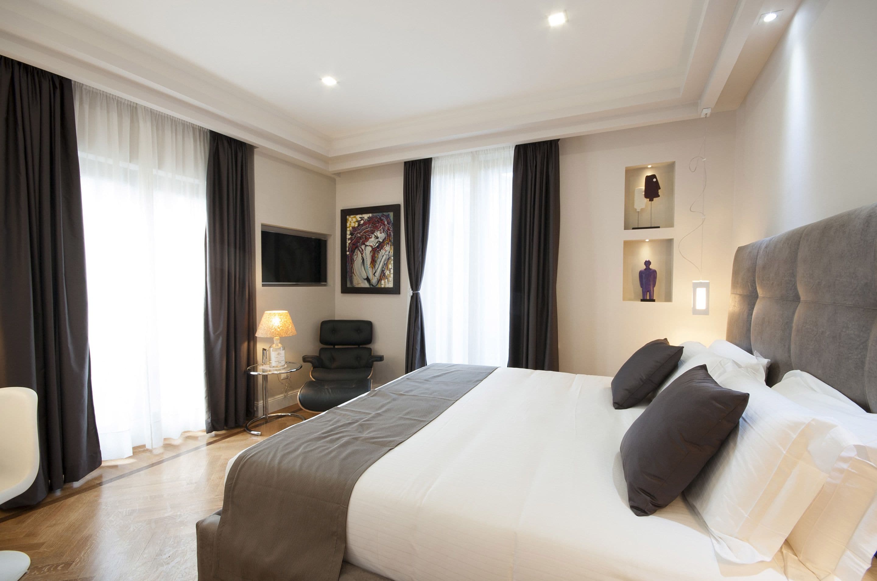 A hotel room with a large bed, a desk, a chair, and a TV on the wall.