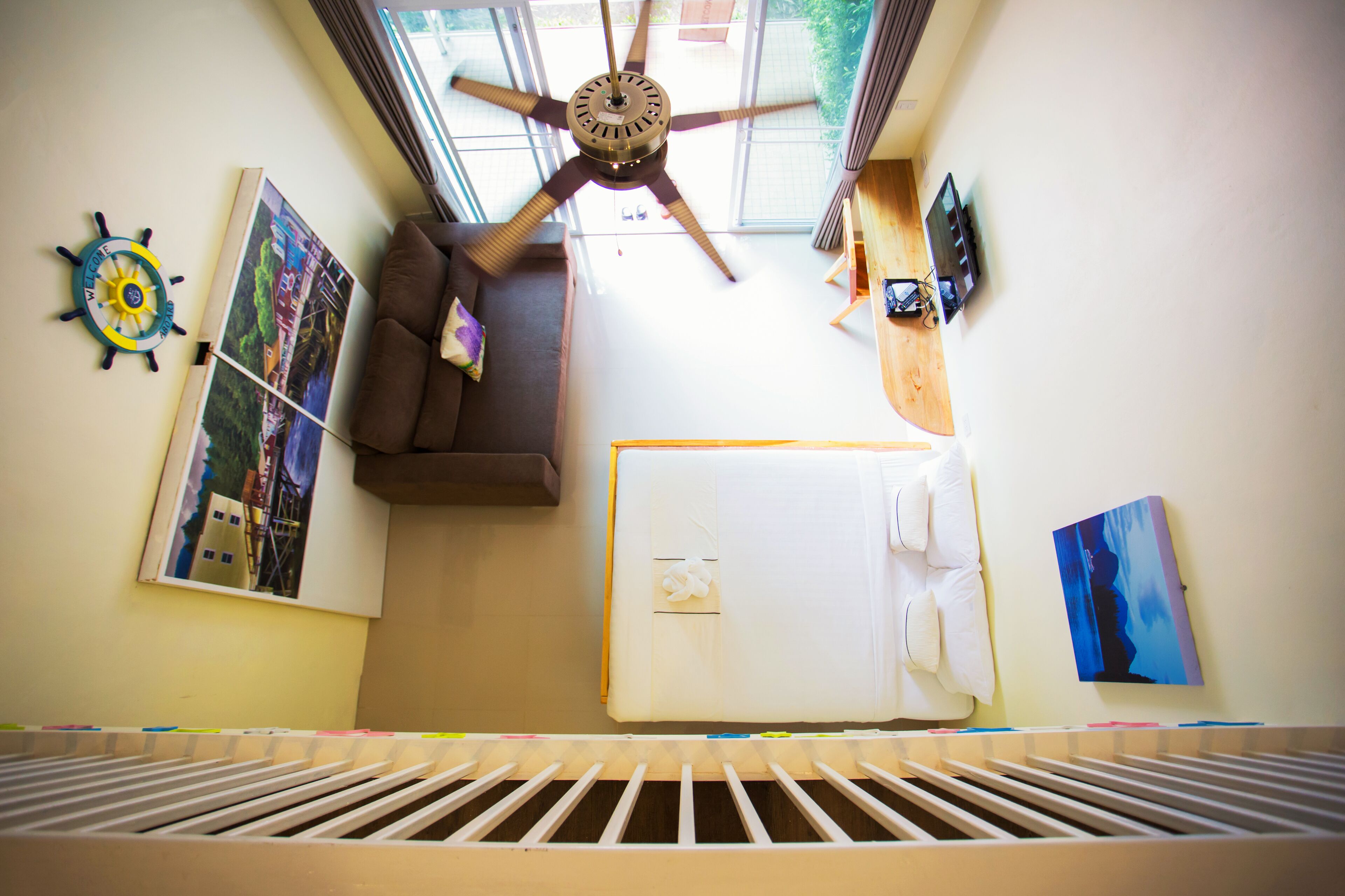 A room with a ceiling fan, a bed, a window, and various wall decorations.