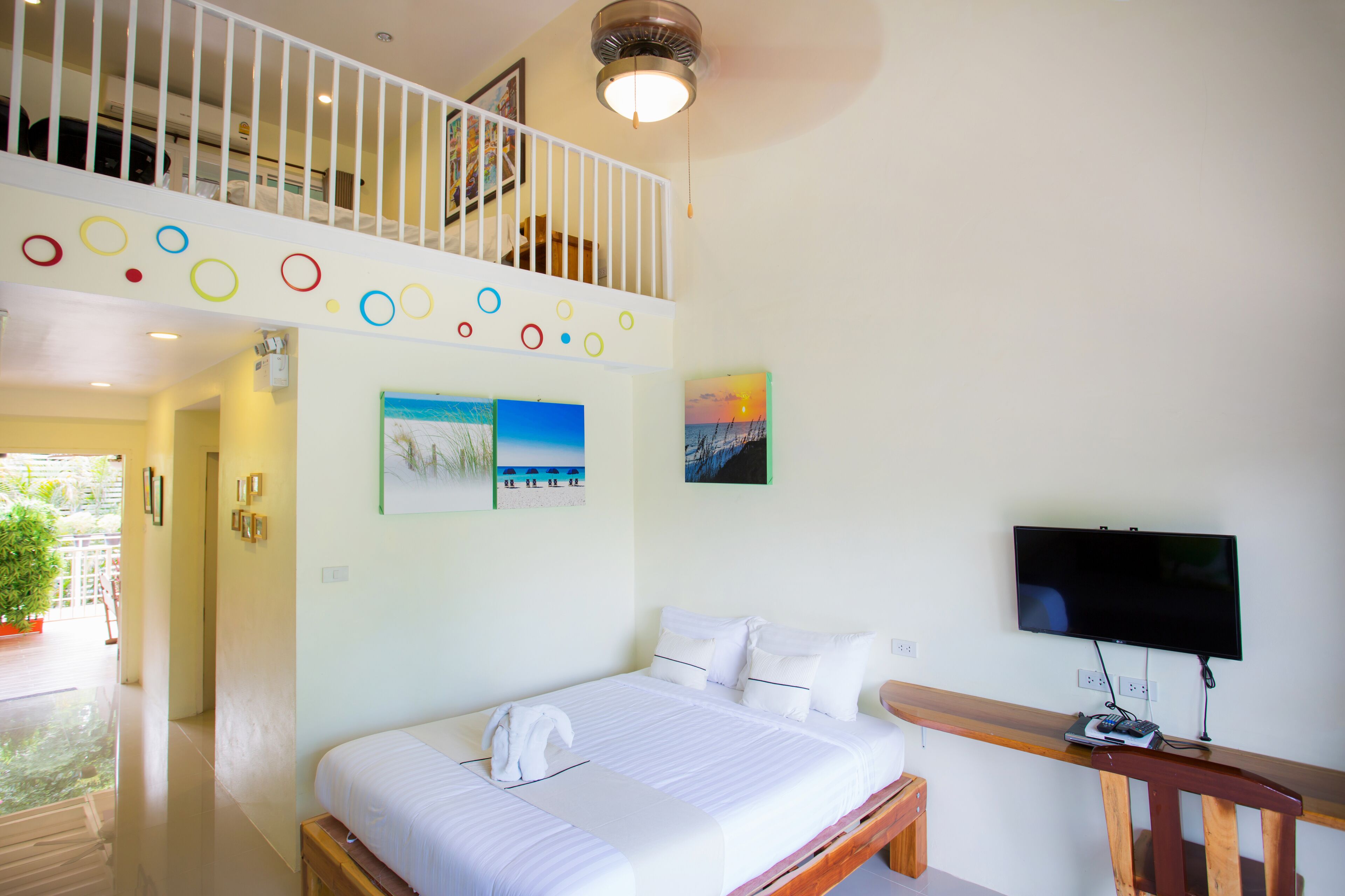 A hotel room with a bed, a TV, and a balcony.