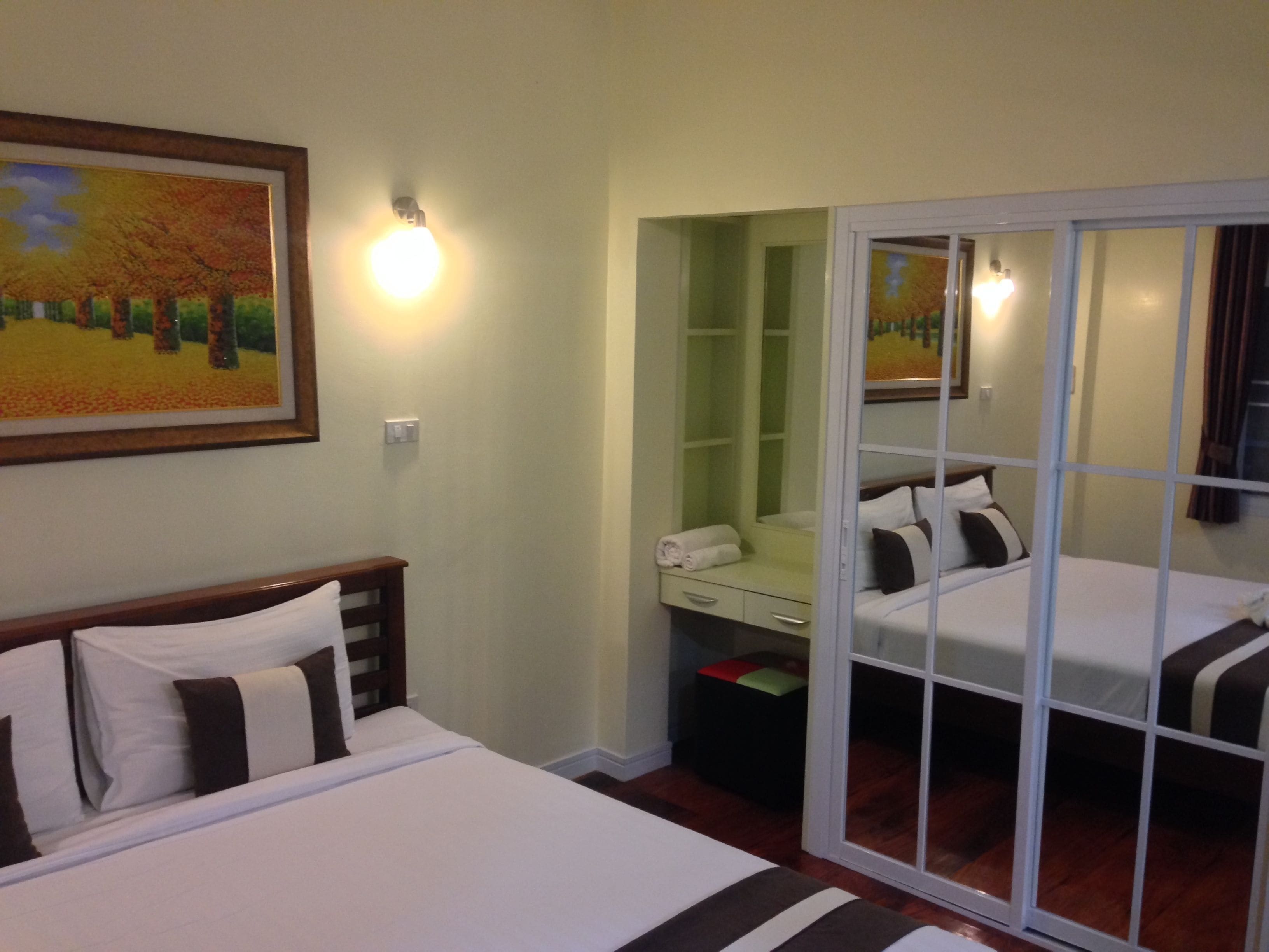 A hotel room with two beds, a green vanity, and a painting on the wall.