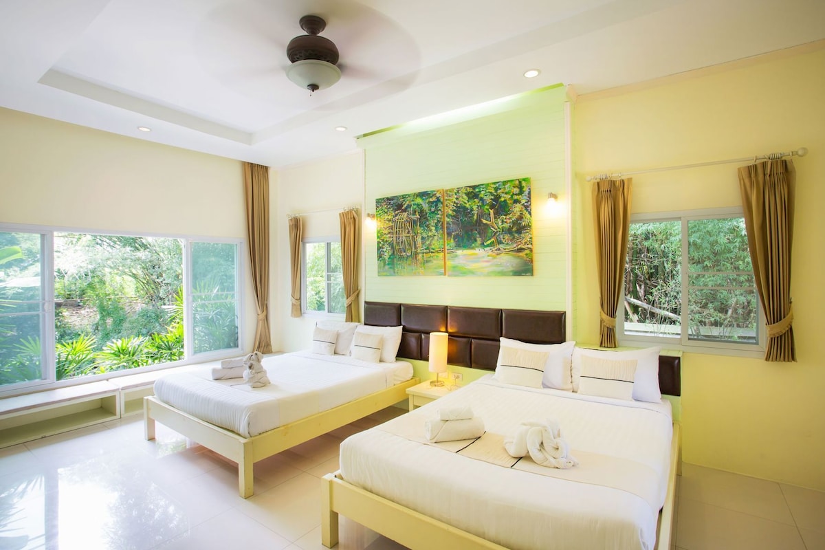 A hotel room with two beds, a large window, and a painting on the wall.