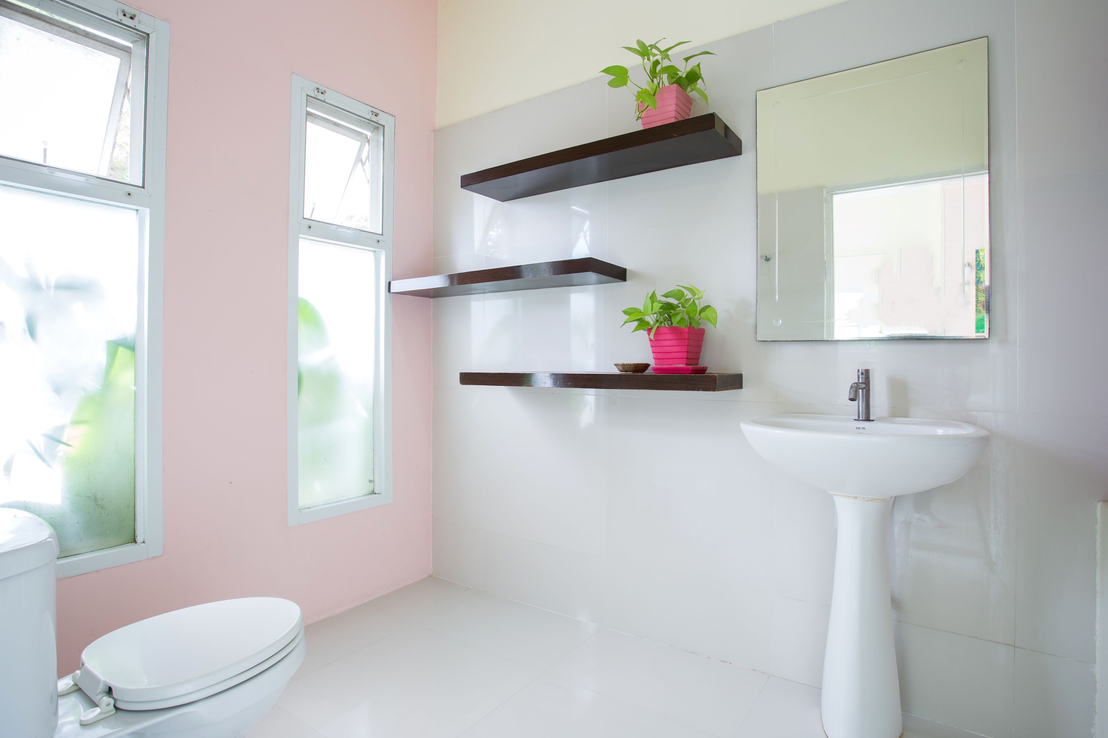 A bathroom with a toilet, a sink, and two windows.