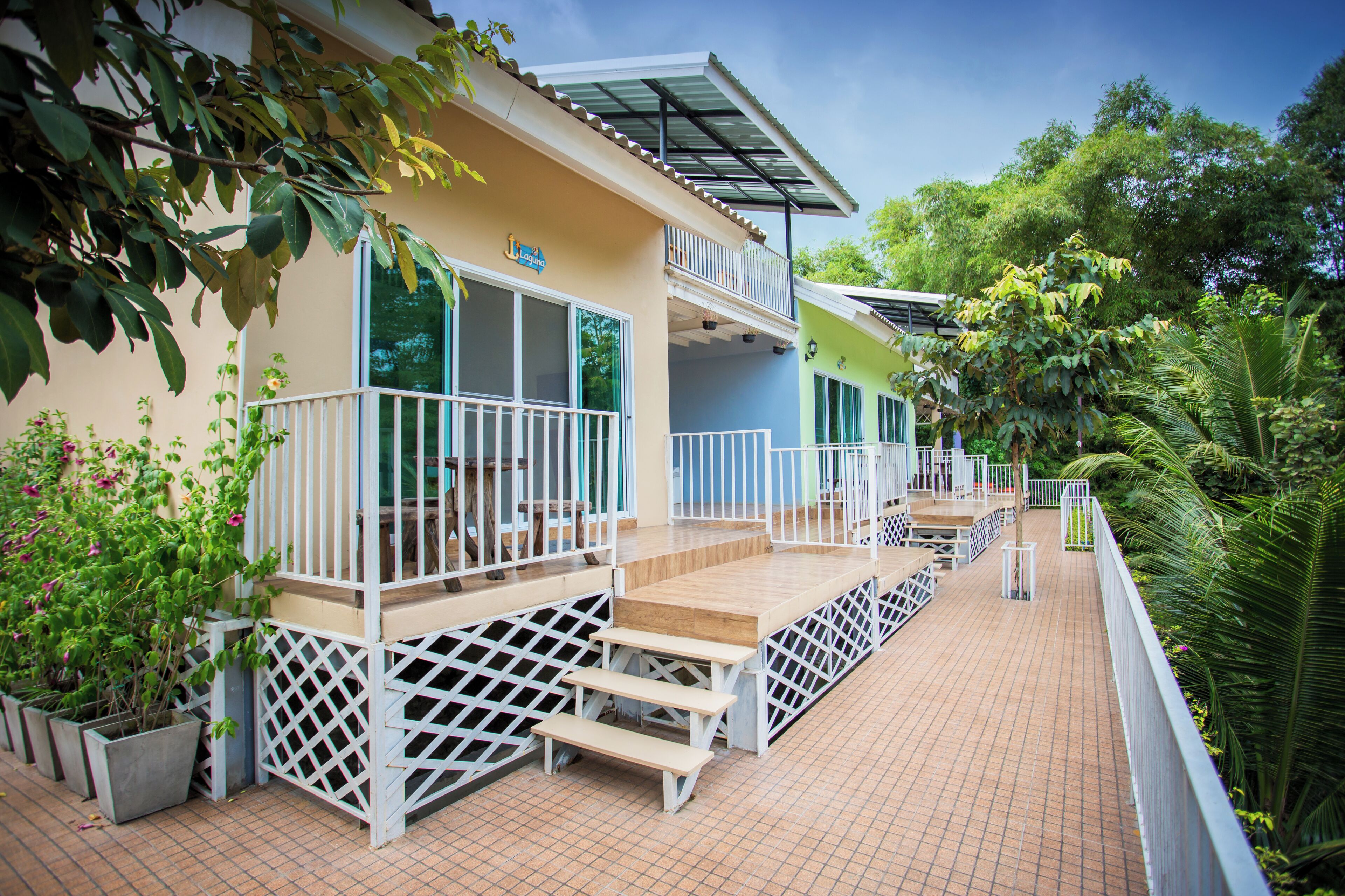A hotel with a covered outdoor area, a pool, and a garden with potted plants.