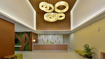 A modern reception area with a wooden reception desk, green seating, and a ceiling with circular light fixtures.