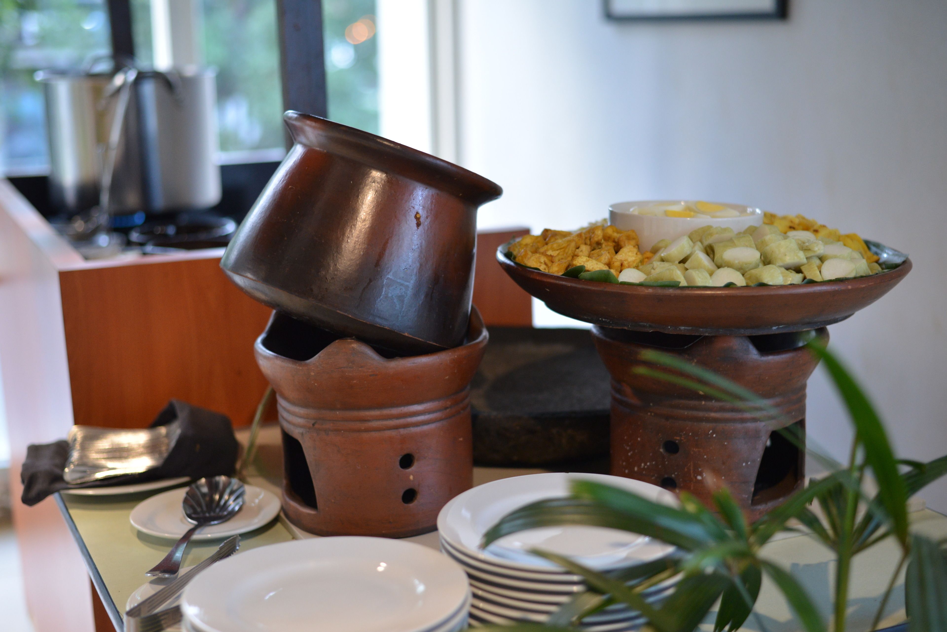 A dining setup with terracotta pots, plates, and a bowl of food.