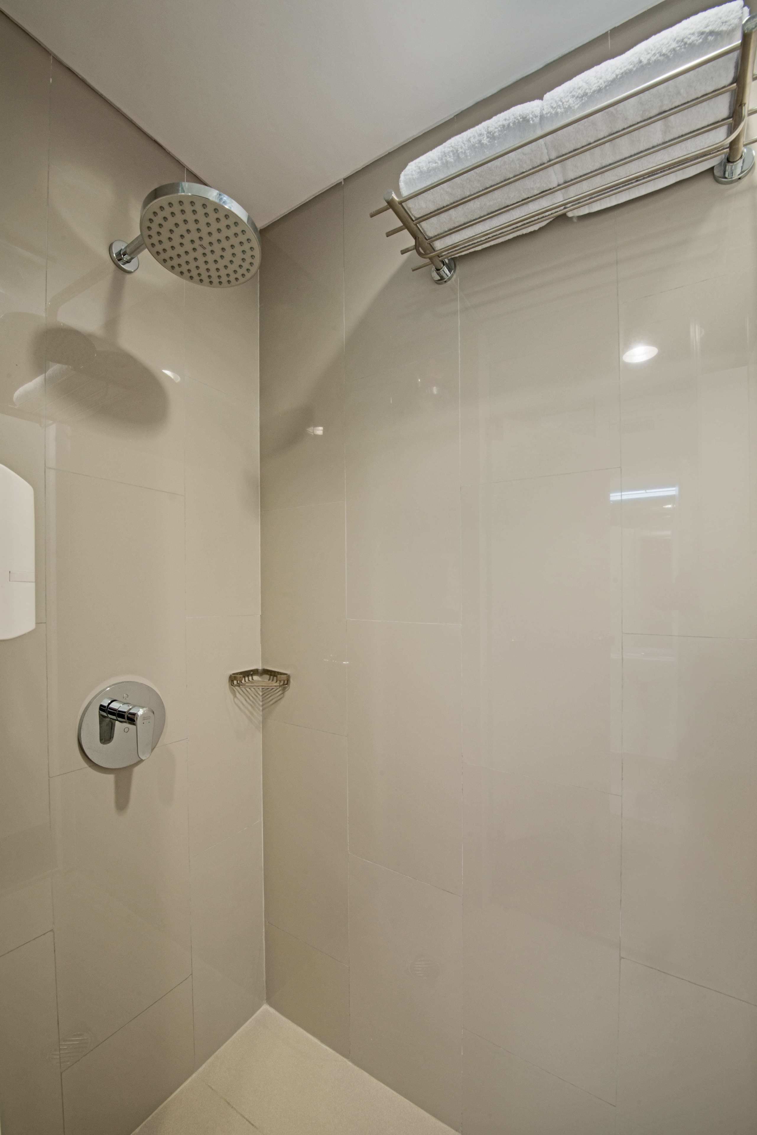 A modern bathroom with a shower, a towel rack, and a soap dispenser.
