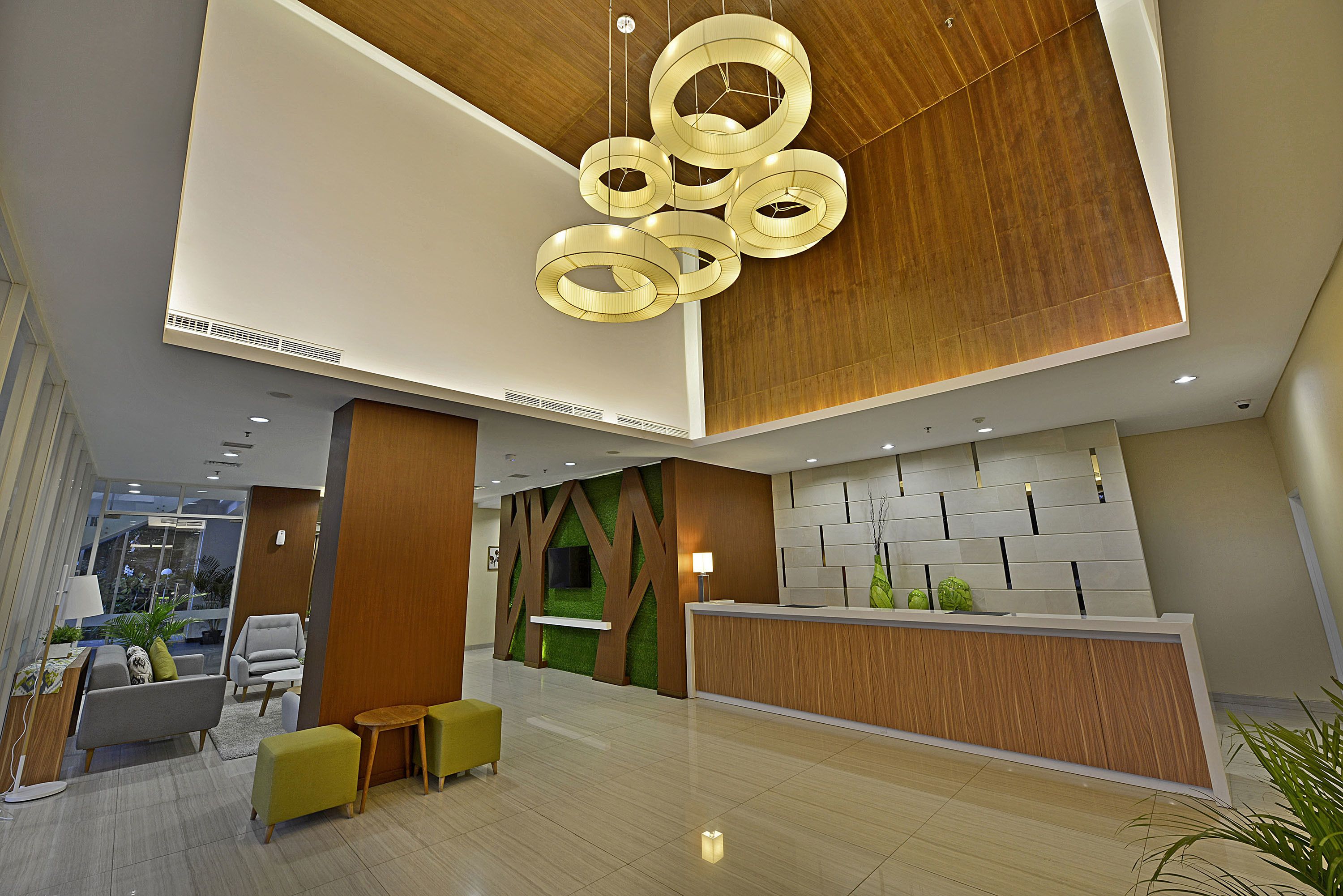Een moderne lobby met een receptiebalie, een zithoek en een bijzondere plafondlamp.