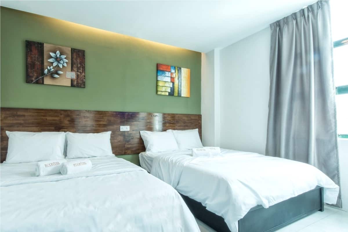 A hotel room with two beds, green walls, and artwork on the wall.
