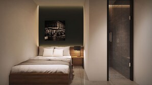 Quarto moderno com cama, mesa de cabeceira, luminária fixada na parede e porta para um banheiro.