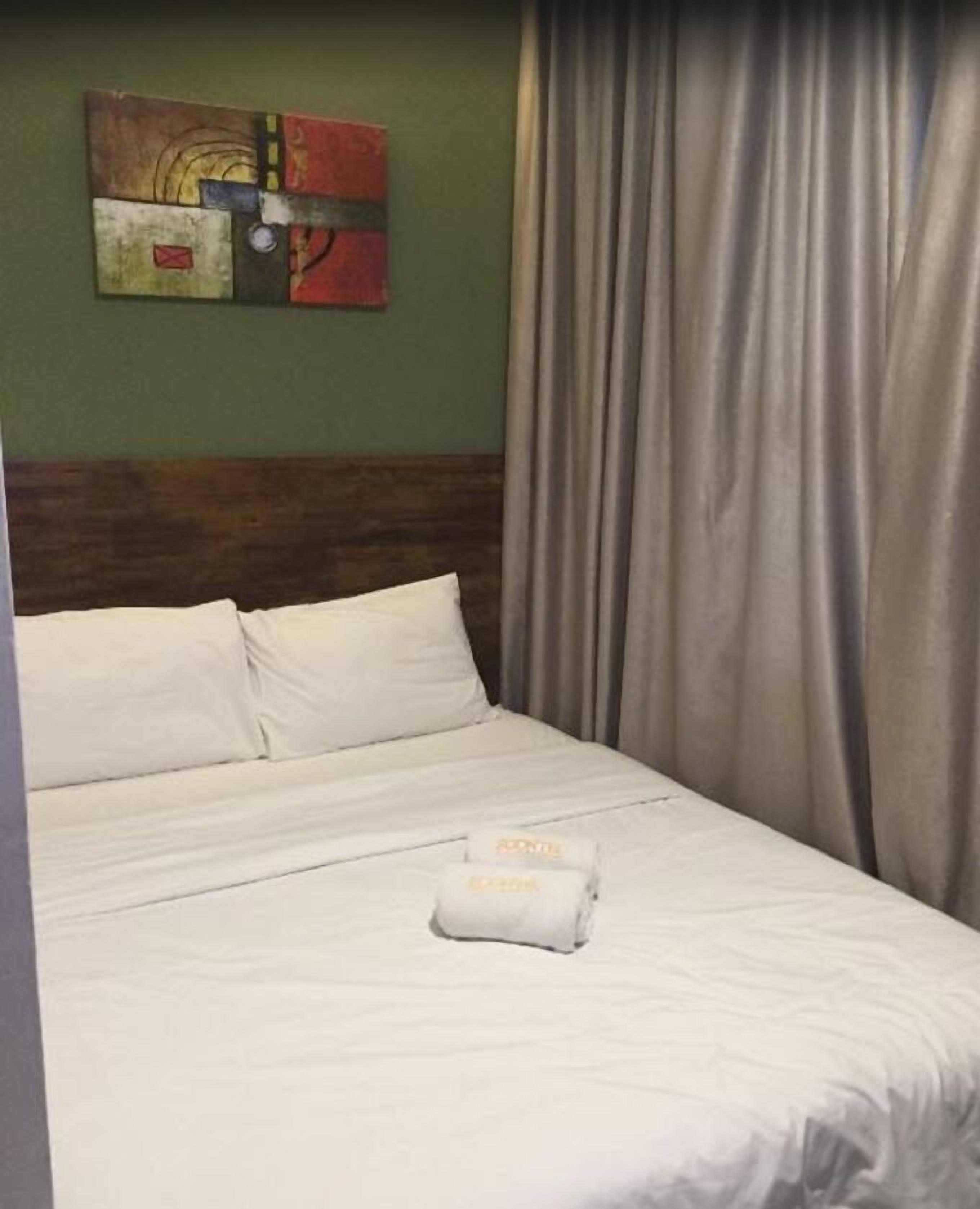 Ett hotellrum med en säng, kuddar, ett täcke och en handduk.