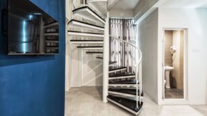 Um interior moderno com escada em espiral, parede azul e banheiro visível.