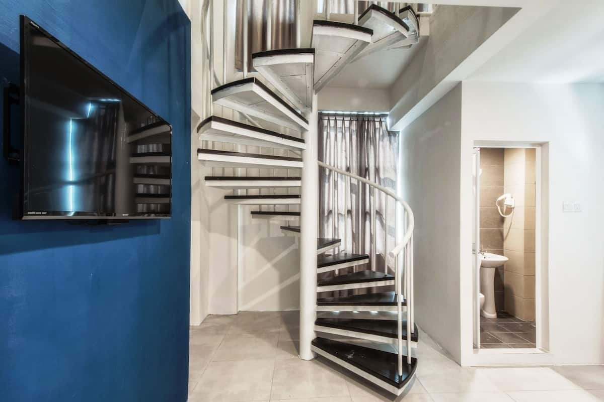 A modern interior with a spiral staircase, a blue accent wall, and a visible bathroom.